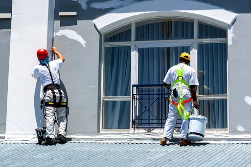 Two painters in harnesses refreshing a downtown Manhattan Beach storefront