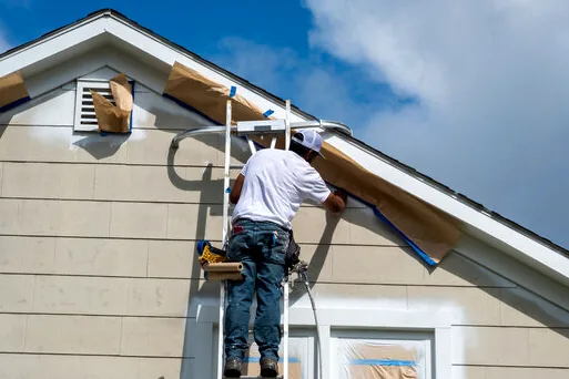 Painter masking windows on a Strand-facing home in Manhattan Beach
